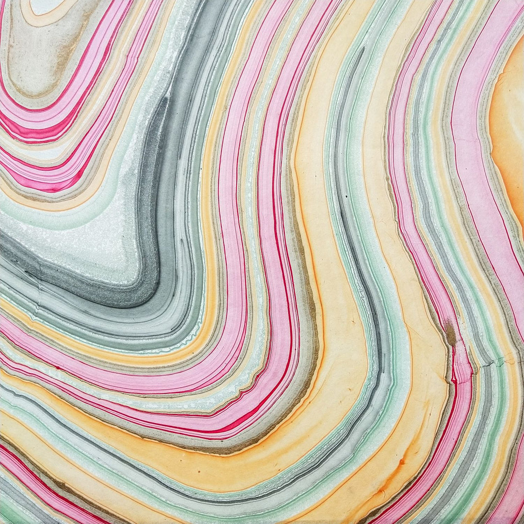 Artistic photo of Kozo Studio handmade paper with a marble effect, mimicking mulberry paper in soft tones of pink, green, yellow, and gray.