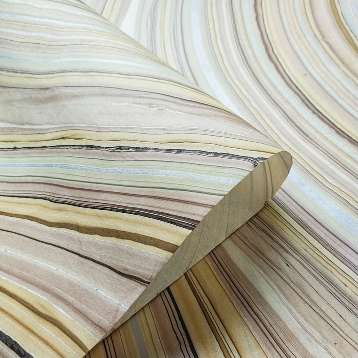 Partially rolled handmade mulberry paper with marble design by Kozo Studio, showcasing natural stone-inspired textures in earthy tones.