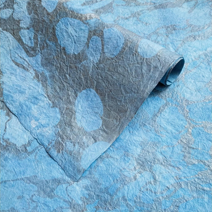 Graceful and artistic handmade mulberry paper by Kozo Studio, featuring fluid marbling and natural creases ideal for creative applications.