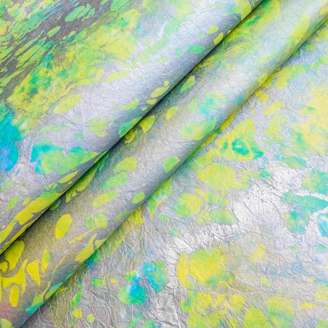 A close-up of Milano Kozo Paper - Design 3 by Kozo Studio reveals an abstract pattern with vibrant lime green, teal, and yellow splashes on a mulberry paper textures, creating a dynamic and eye-catching visual effect.