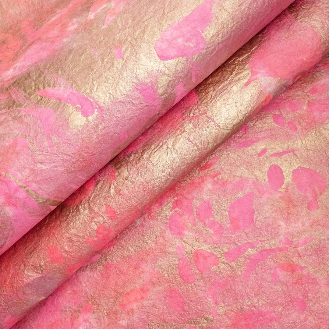 Milano Kozo Paper - Design 4 by Kozo Studio features a close-up of crumpled, metallic-finished paper with a mulberry texture, shimmering in soft pink and gold hues that fold smoothly into abstract patterns.
