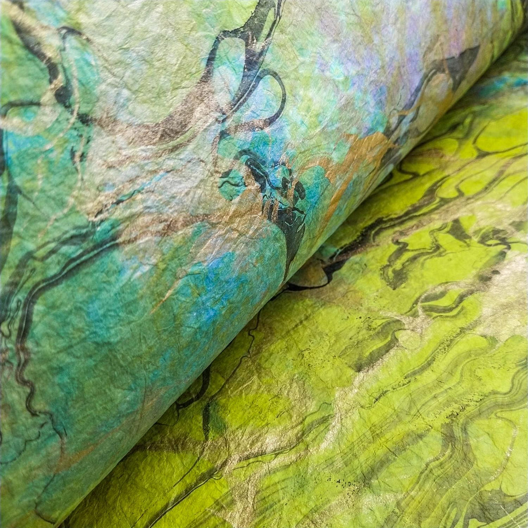 A detailed close-up of Milano Kozo Paper - Design 5 from Kozo Studio features swirling, abstract patterns in iridescent mulberry paper, showcasing vibrant greens and blues that evoke a textured artistic landscape.