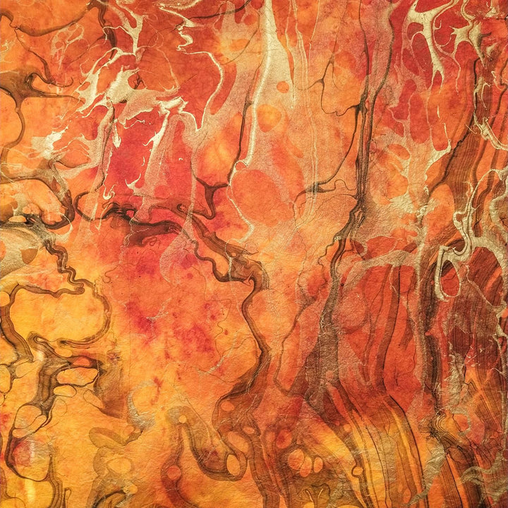 Handcrafted mulberry paper by Kozo Studio in a marbled abstract pattern of warm hues and metallic highlights, ideal for craft or design projects.
