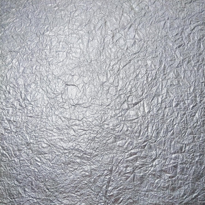 Crumpled texture of silver metallic handmade paper from Kozo Studio, showcasing flexible and fabric-like mulberry paper.