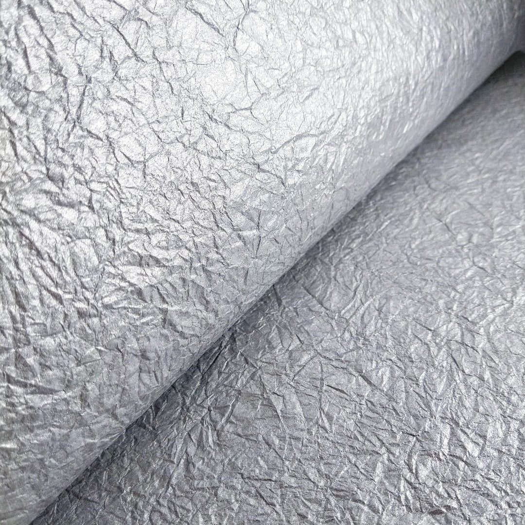 Close-up of shimmering handmade mulberry paper in silver, featuring a soft matte reverse and flexible texture by Kozo Studio.