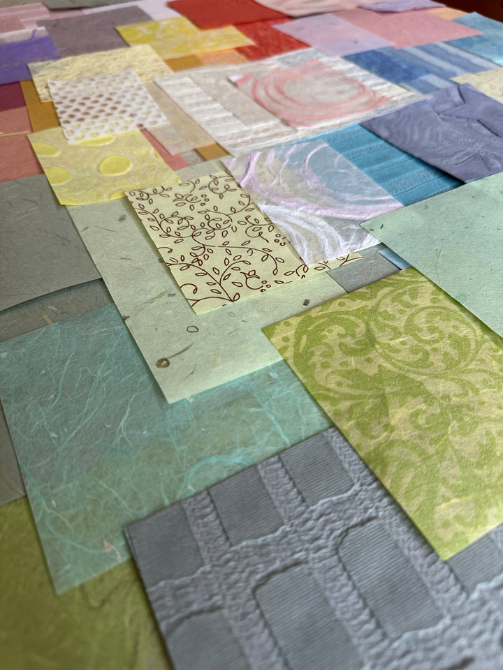 A close-up of Kozo Studios Mulberry Paper Scrap Pack (100 Pieces) - Spring Pastel, featuring a colorful patchwork of overlapping paper squares with diverse textures and patterns like florals, swirls, and geometric designs in pastel and vibrant hues.