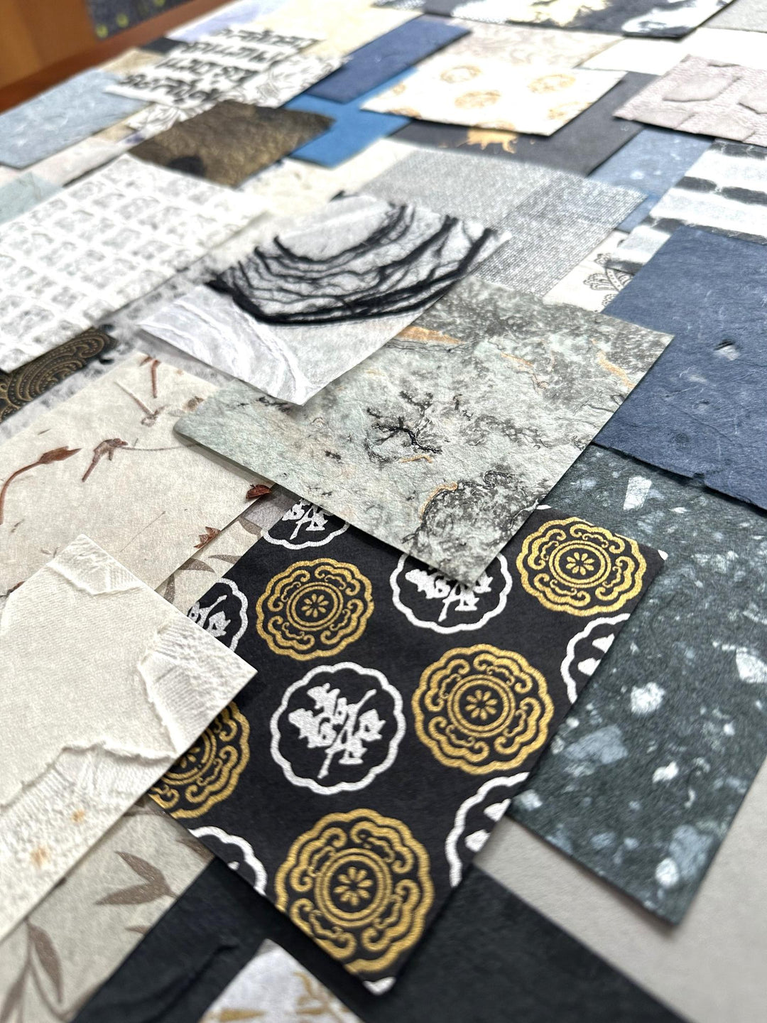 Artistic photo of Kozo Studio's mulberry paper variety pack. This handmade paper collection includes 100 unique scraps, offering endless creative possibilities in blue, white, and gold hues.