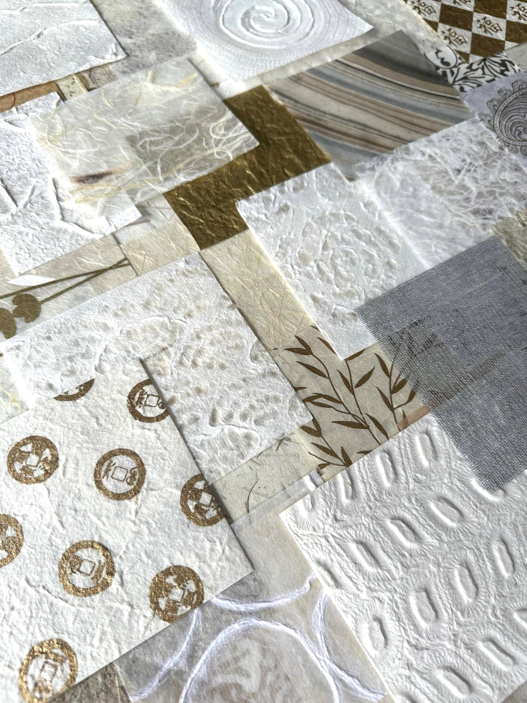 The Mulberry Paper Scrap Pack (100 Pieces) - Golden Harvest by Kozo Studio features textured squares of mulberry and rice paper in white, cream, and gold hues with swirls, stripes, and floral prints that form a stunning patchwork effect.