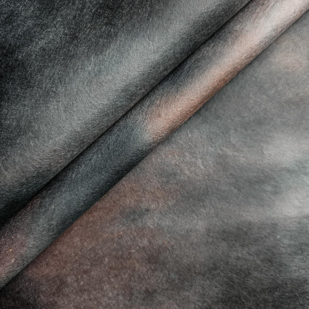 Close-up of handmade mulberry paper from Kozo Studio in an ombre gradient of deep midnight umber hues, ideal for creative projects and fine paper crafts.