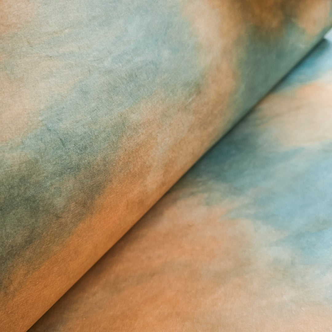 A close-up of a Kozo Studio magazine featuring Ombre Kozo Paper (#6 Woodland Overcast) with abstract art. The design blends blue and orange hues, creating a cloud-like texture on Mulberry rice paper