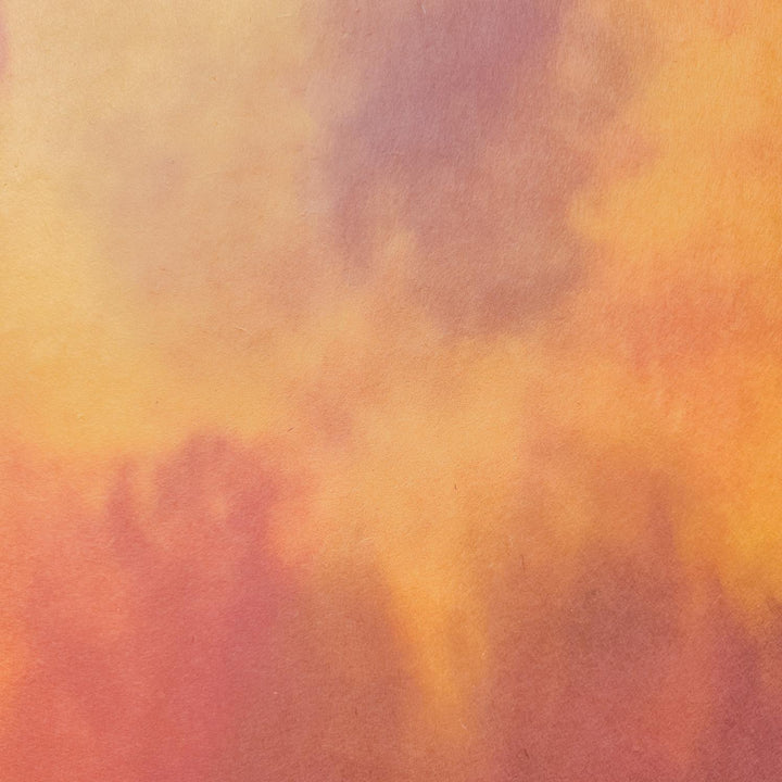 The Ombre Kozo Paper (#7 Amber Dawn) by Kozo Studio features a textured abstract background with warm orange, yellow, and reddish-brown tones blending on canvas of mulberry paper, creating a cloudy, sunset-like effect.