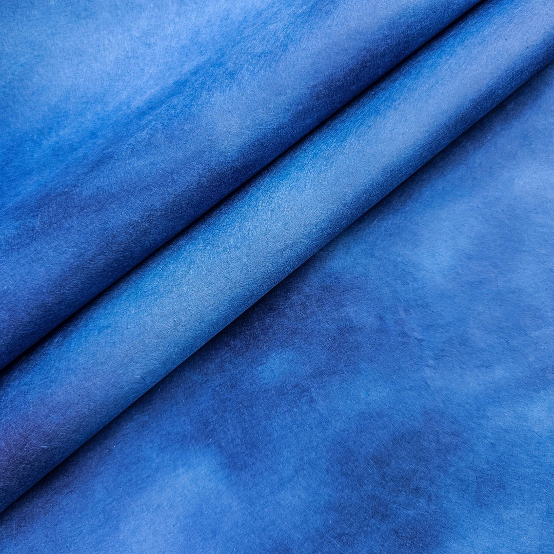 Hand-colored ombre mulberry paper from Kozo Studio featuring a seamless gradient of vibrant blue shades, ideal for handmade paper art and creative projects.