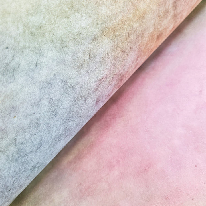 A close-up shows two overlapping sheets of Kozo Studios Ombre Kozo Paper (#4 Ethereal Rainbow) in pastel hues. The left mulberry sheet fades from light gray to green, and the right from soft pink to peach,.