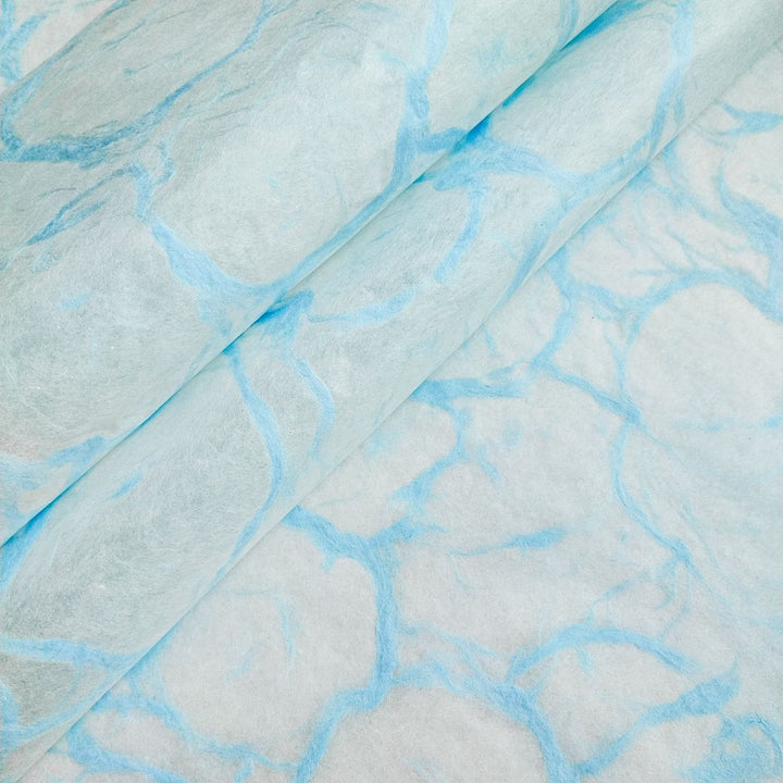 Blue marbled design on white mulberry paper by Kozo Studio, captured in a close-up of their Ripple Kozo handmade paper collection.