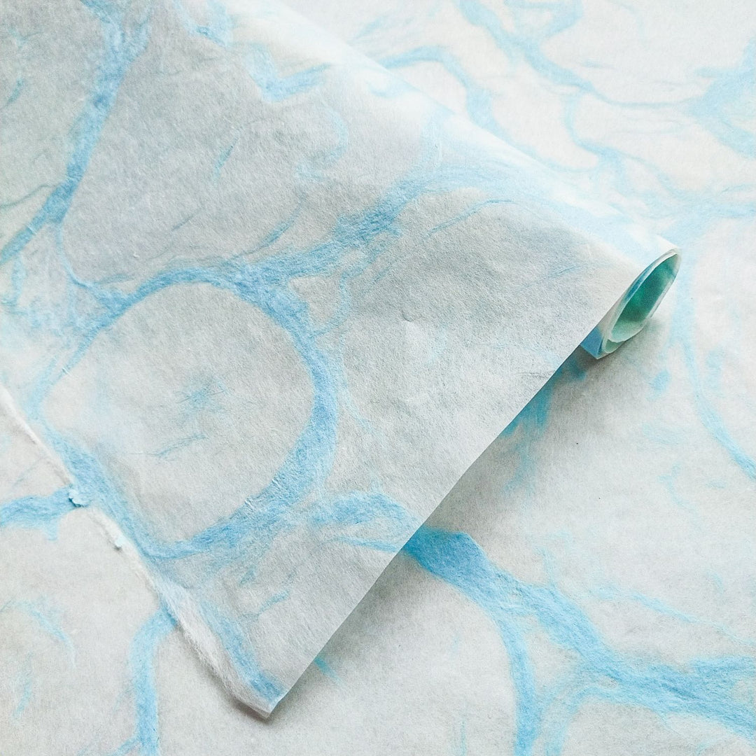 Detailed view of Ripple Kozo Blue on White from Kozo Studio, showcasing elegant light blue patterns on smooth textured handmade mulberry paper.