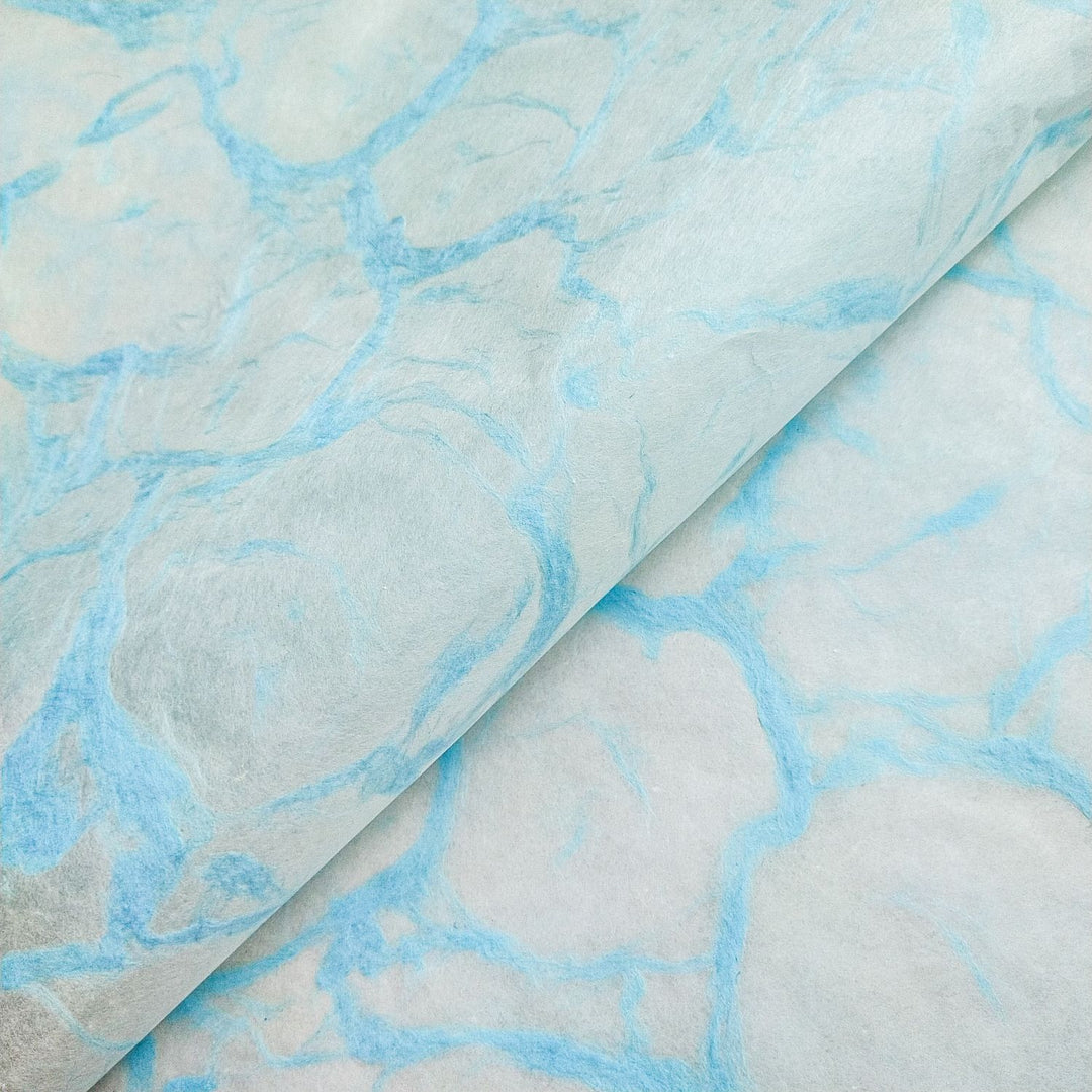 Close-up of Kozo Studio handmade paper in Ripple Kozo Blue on White, featuring soft marbled textures inspired by water ripples on mulberry paper.
