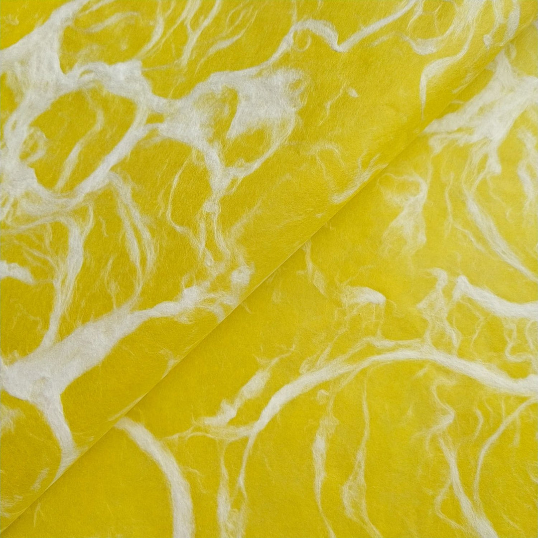 Smooth textured surface of Kozo Studio mulberry paper, showcasing the Ripple Kozo design with marble-like white fibers on yellow handmade paper.