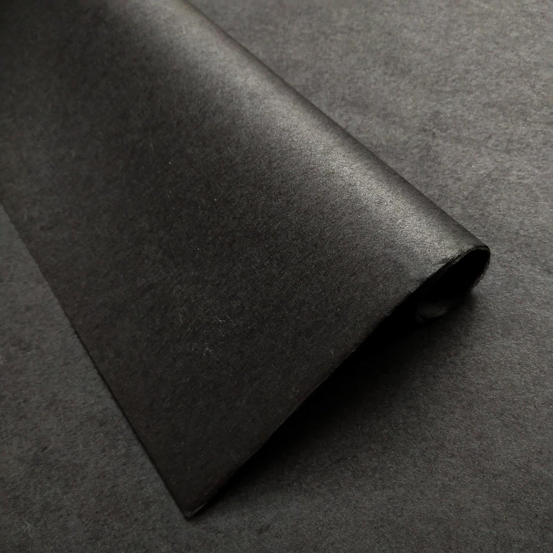Detailed image of solid-colored black Kozo Studio mulberry paper highlighting the handmade paper texture and shadows.
