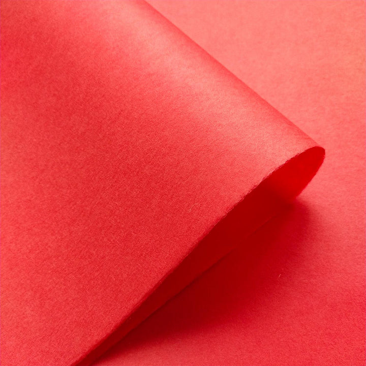Solid-colored handmade paper in cherry red from Kozo Studio, made with mulberry fibers and shown in detailed texture.