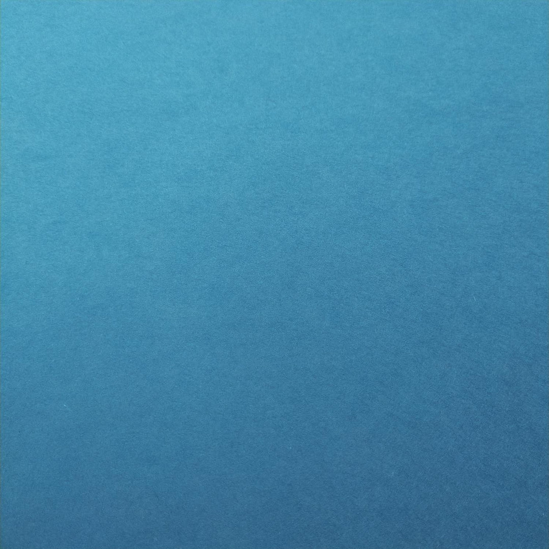 Kozo Studio mulberry paper in vibrant cobalt blue with lighting that emphasizes the fine grain of handmade paper sheets.