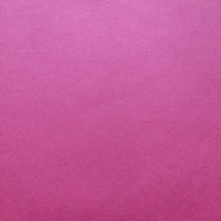 Handmade paper in a bold fuchsia hue from Kozo Studio, with a curled corner revealing the smooth surface and depth of mulberry fiber texture.