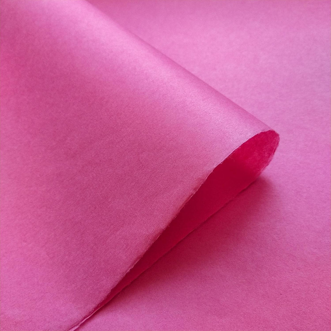 Detailed view of Kozo Studio handmade mulberry paper, showcasing the vivid fuchsia color and natural texture from traditional papermaking techniques.