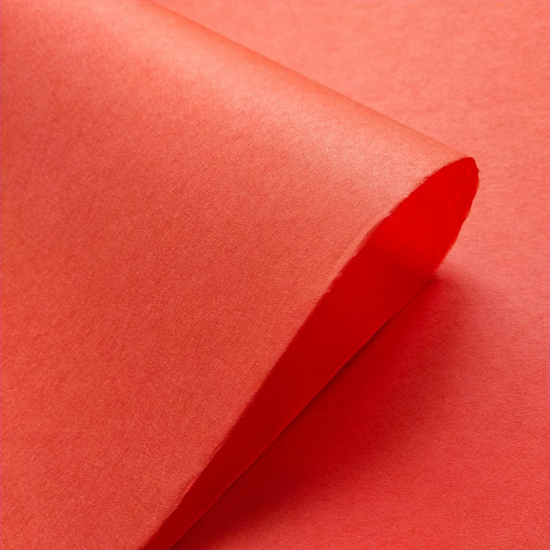 Textured close-up of handmade Kozo Studio mulberry paper in Nasturtium, displaying diagonal folds and the natural sheen of high-quality paper.
