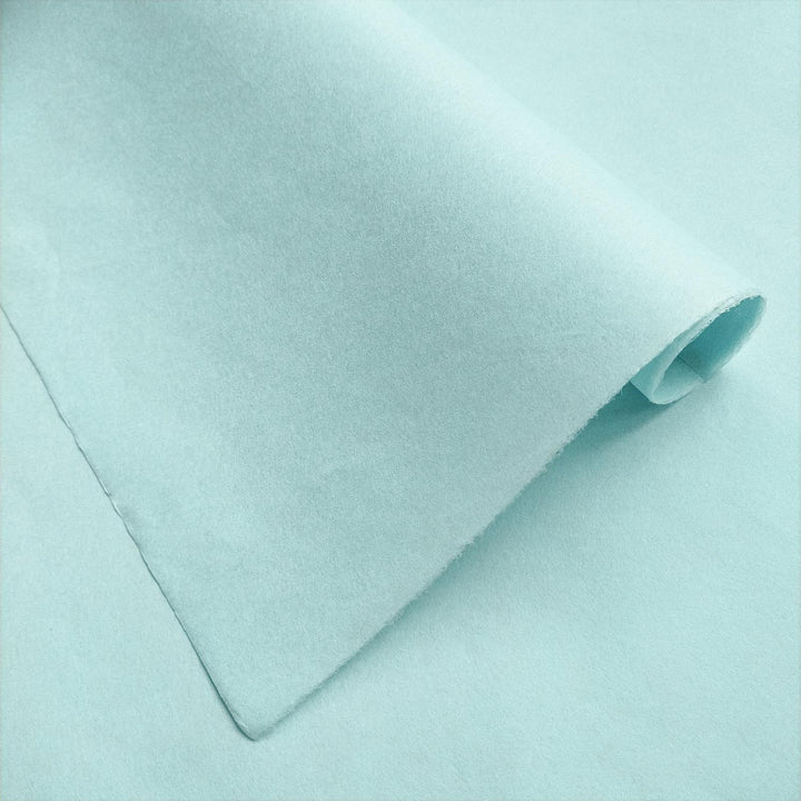 Diagonal fold of Kozo Studio handmade paper in solid sky blue, revealing subtle shading and the natural texture of premium mulberry paper.