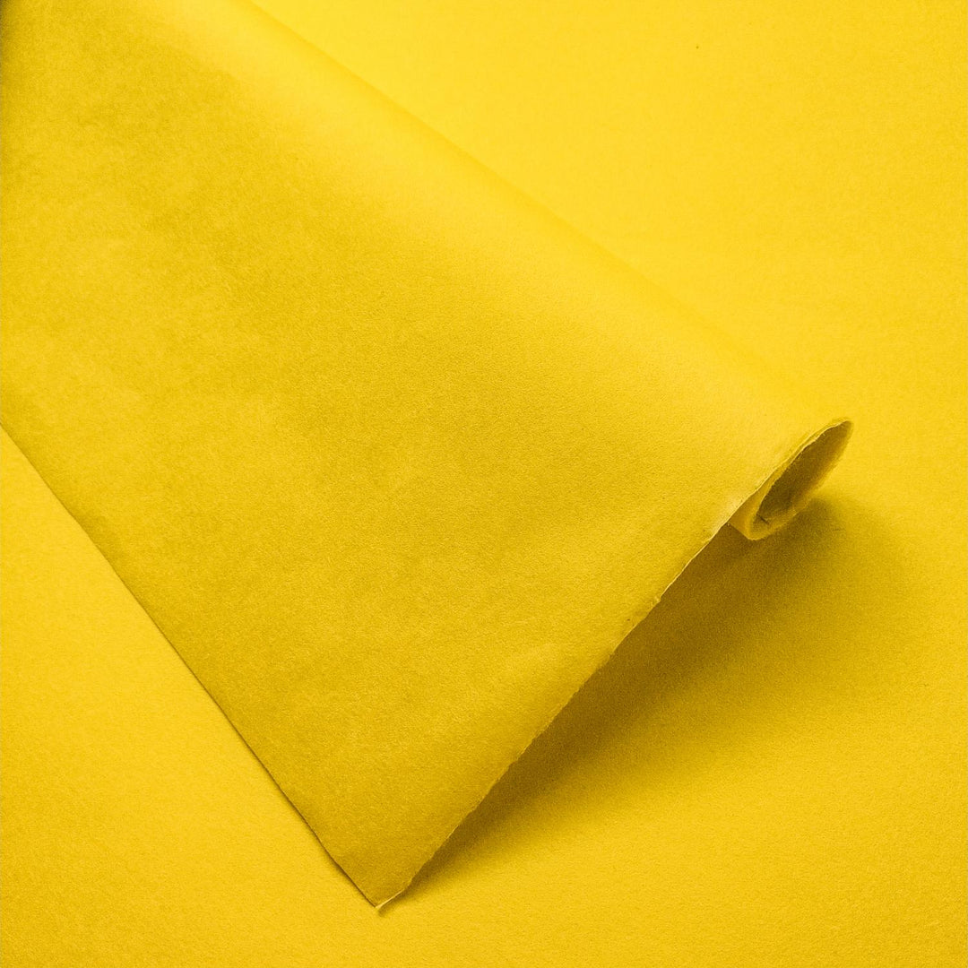 Handmade paper in vibrant canary yellow from Kozo Studio, showcasing soft folds and delicate shadows on premium mulberry paper.