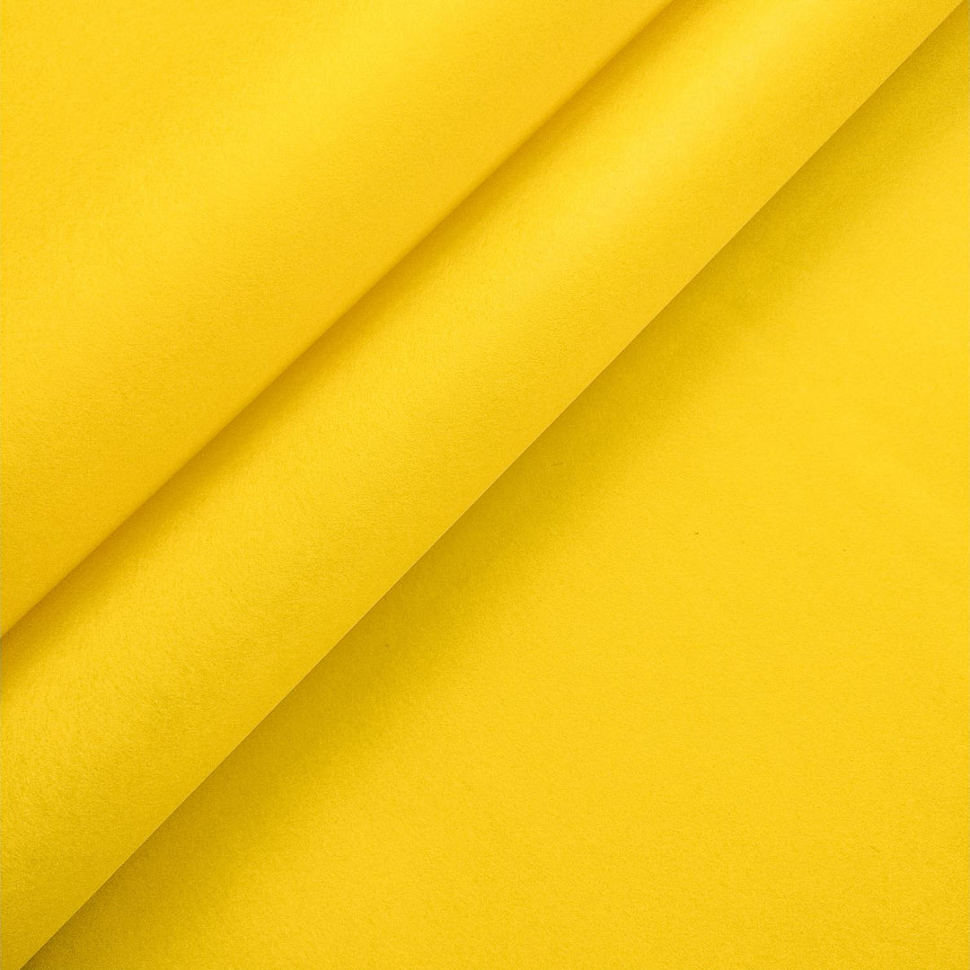 Canary yellow mulberry paper by Kozo Studio, folded diagonally with layered shadows highlighting its smooth handmade texture.
