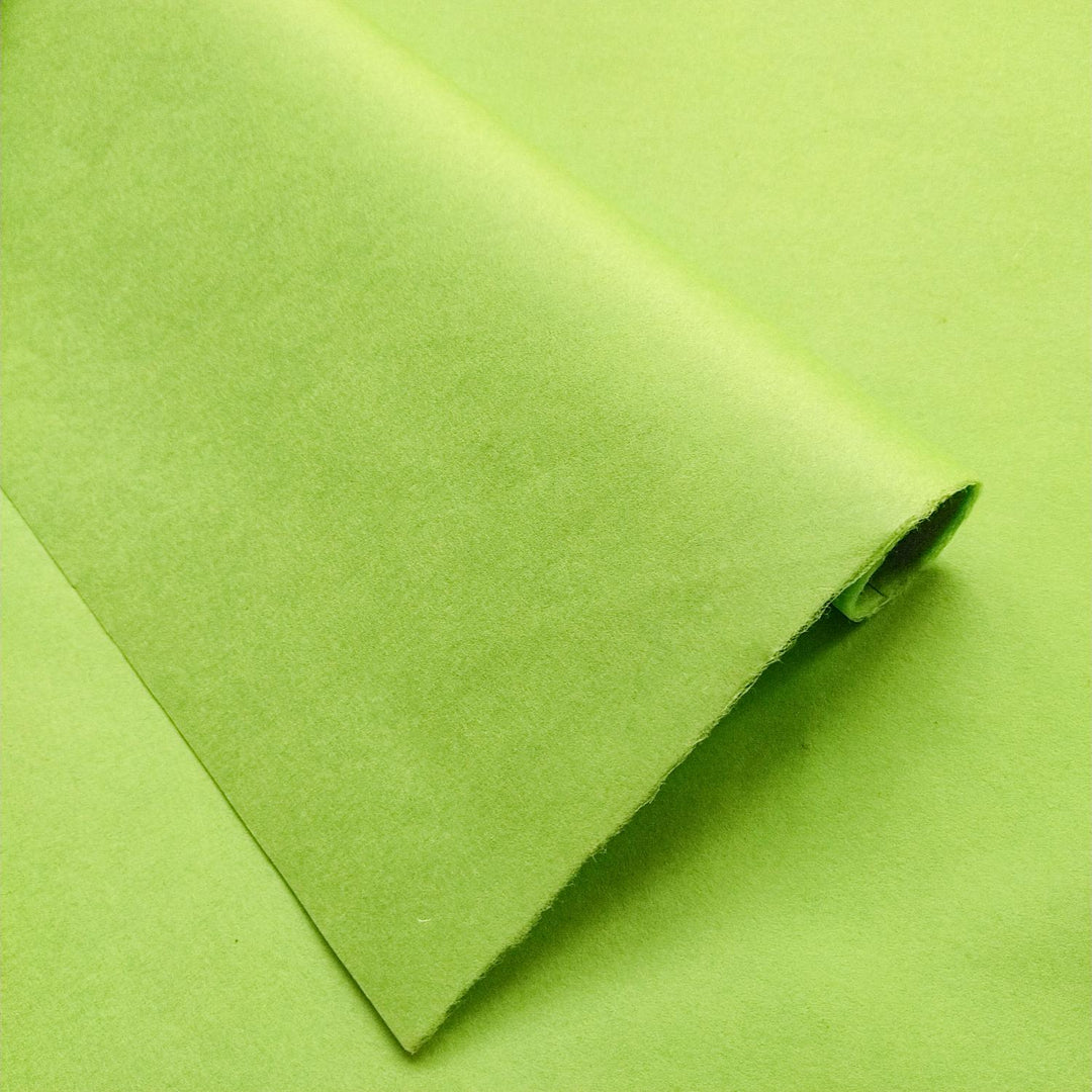 The partially rolled Solid-Colored Kozo Paper in olive green from Kozo Studio enchants with its smooth texture and vibrant hue.