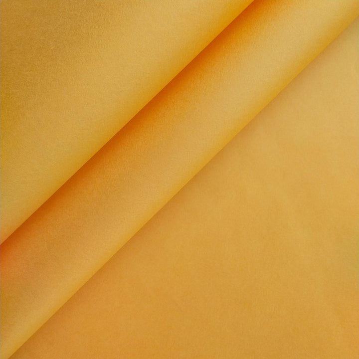 Close-up of saffron-colored mulberry paper by Kozo Studio showcasing its handmade texture, soft shadowing, and subtle color gradients across folded diagonal edges.
