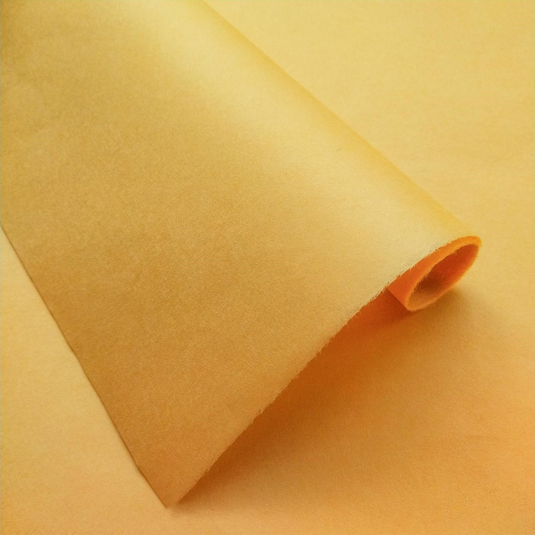 Handmade paper in a rich saffron hue by Kozo Studio, folded to display delicate textures and the natural depth of premium mulberry paper.