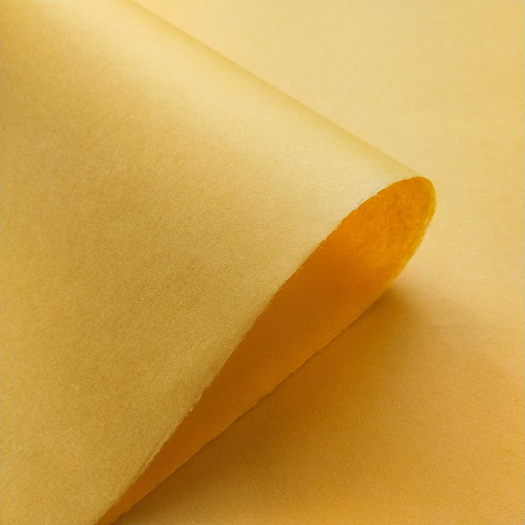 Textured diagonal folds of saffron-toned handmade mulberry paper by Kozo Studio, with soft shadows enhancing the natural beauty and depth of the material.