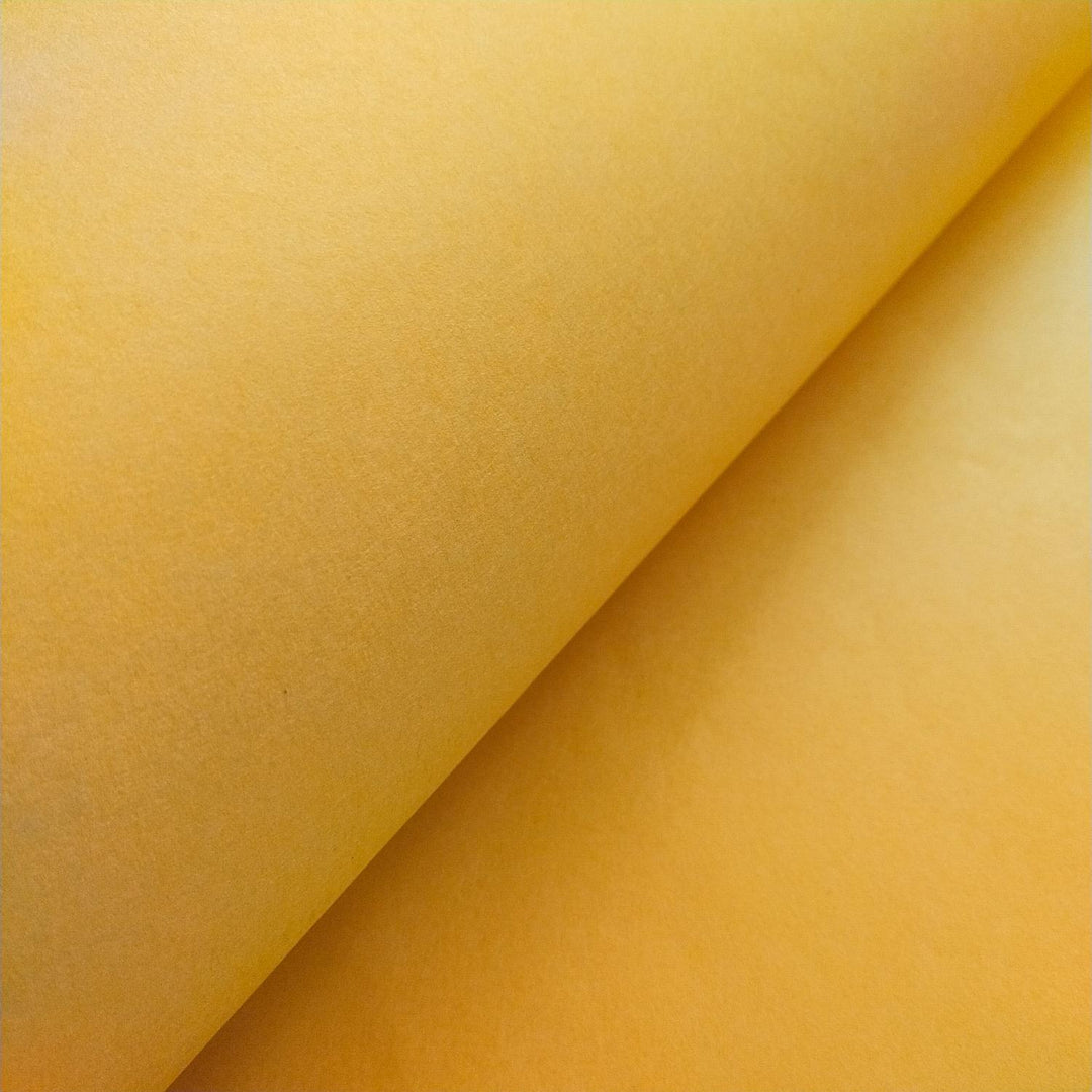 A vivid capture of Kozo Studio saffron handmade paper, folded to reveal the unique fibers and tonal richness characteristic of authentic mulberry paper.