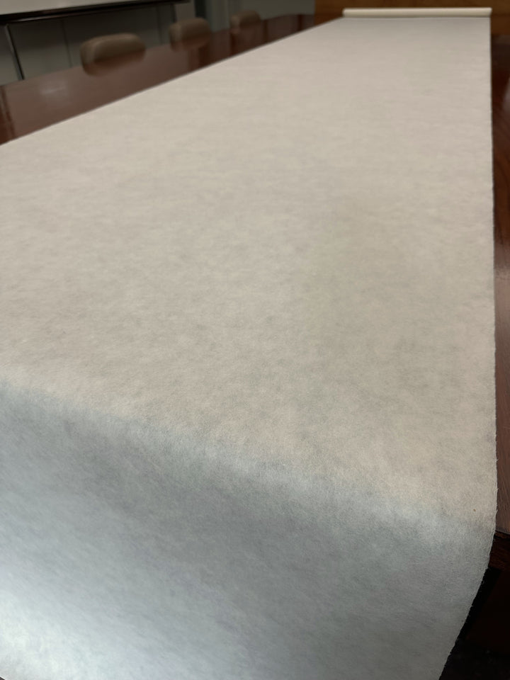 A close-up shows a Thin Natural Kozo Paper Roll (45 gsm) from Kozo Studio, unrolled across a polished wooden table in a meeting room with chairs in the background.