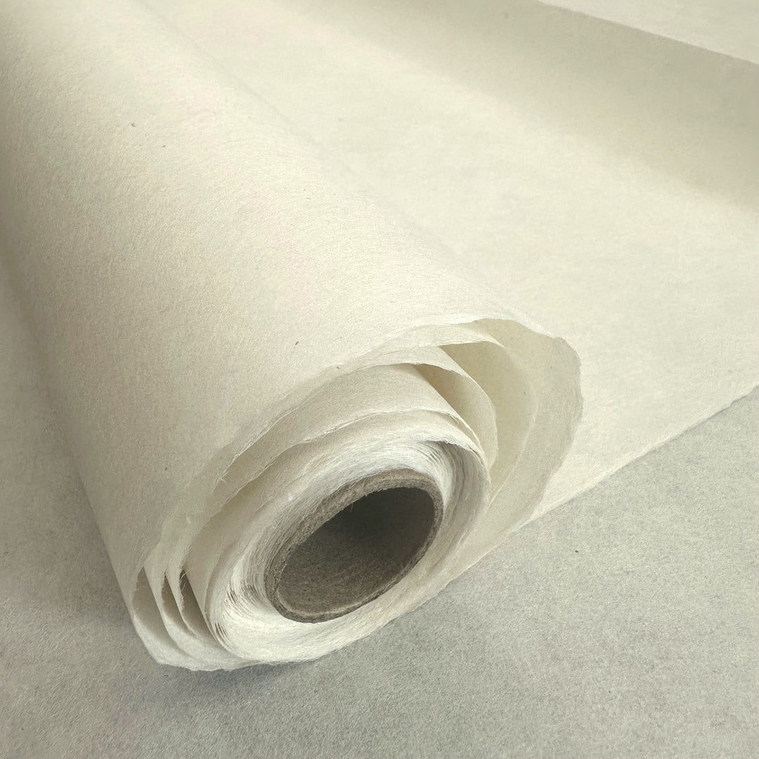 A close-up of a rolled Thin Natural Kozo Paper Roll (45 gsm) by Kozo Studio on a flat surface, highlighting its layered texture and inner cardboard tube.