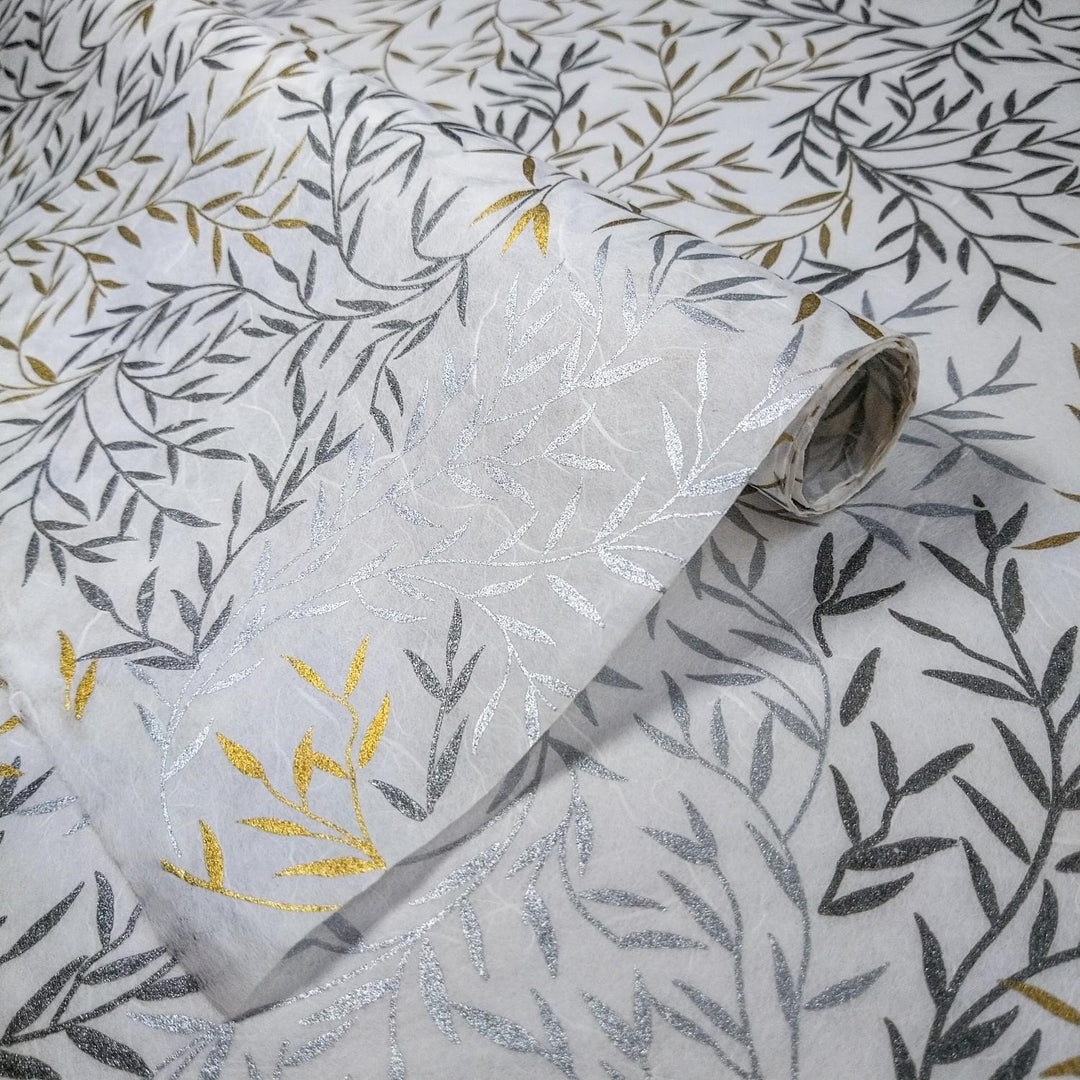 Shimmering handmade paper from Kozo Studio featuring metallic leafy designs in gold and silver on overlapping sheets of white mulberry paper.