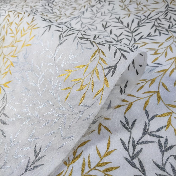 Overlapping sheets of Kozo Studio handmade paper showing metallic leaf patterns in gold and silver on white mulberry paper with a smooth texture.