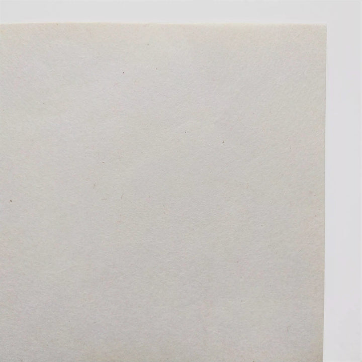 Textured surface of uncoated mulberry paper by Kozo Studio, ideal for inkjet printing, calligraphy, or decoupage; the handmade paper curls softly on a white backdrop.