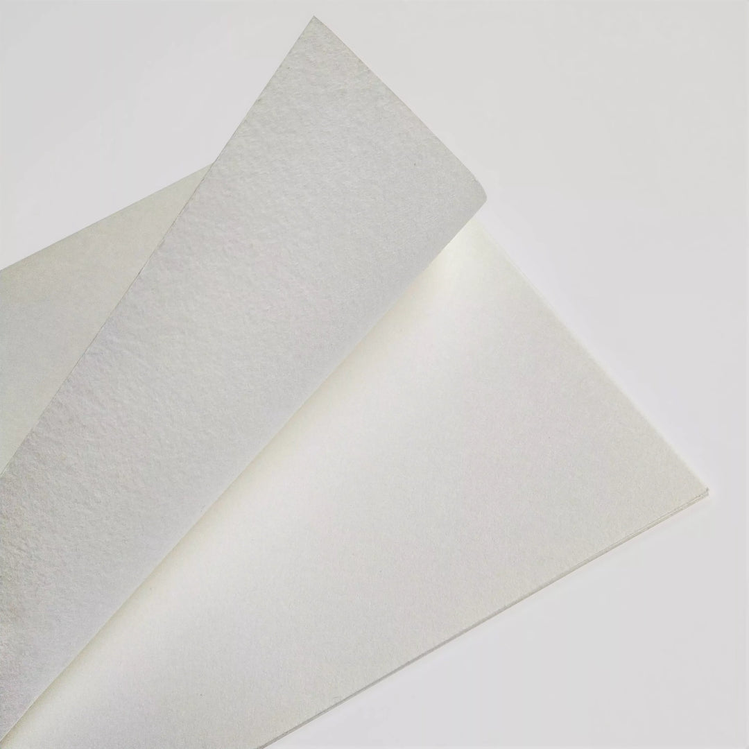 Two Thick White Kozo Paper Rolls (200 gsm) by Kozo Studio, ideal for calligraphy, painting, drawing, and both digital and traditional printing, overlap on a white surface with one corner slightly raised.