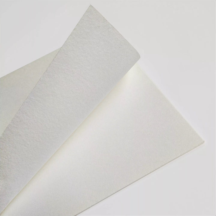 Two Thick White Kozo Paper Rolls (200 gsm) by Kozo Studio, ideal for calligraphy, painting, drawing, and both digital and traditional printing, overlap on a white surface with one corner slightly raised.