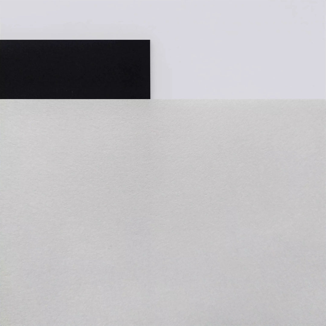 A black rectangle overlaps the top edge of a large white textured surface, evoking calligraphic art on Kozo Studio’s Thick White Kozo Paper Roll (200 gsm), all arranged on a smooth light gray background in a minimal, geometric style.