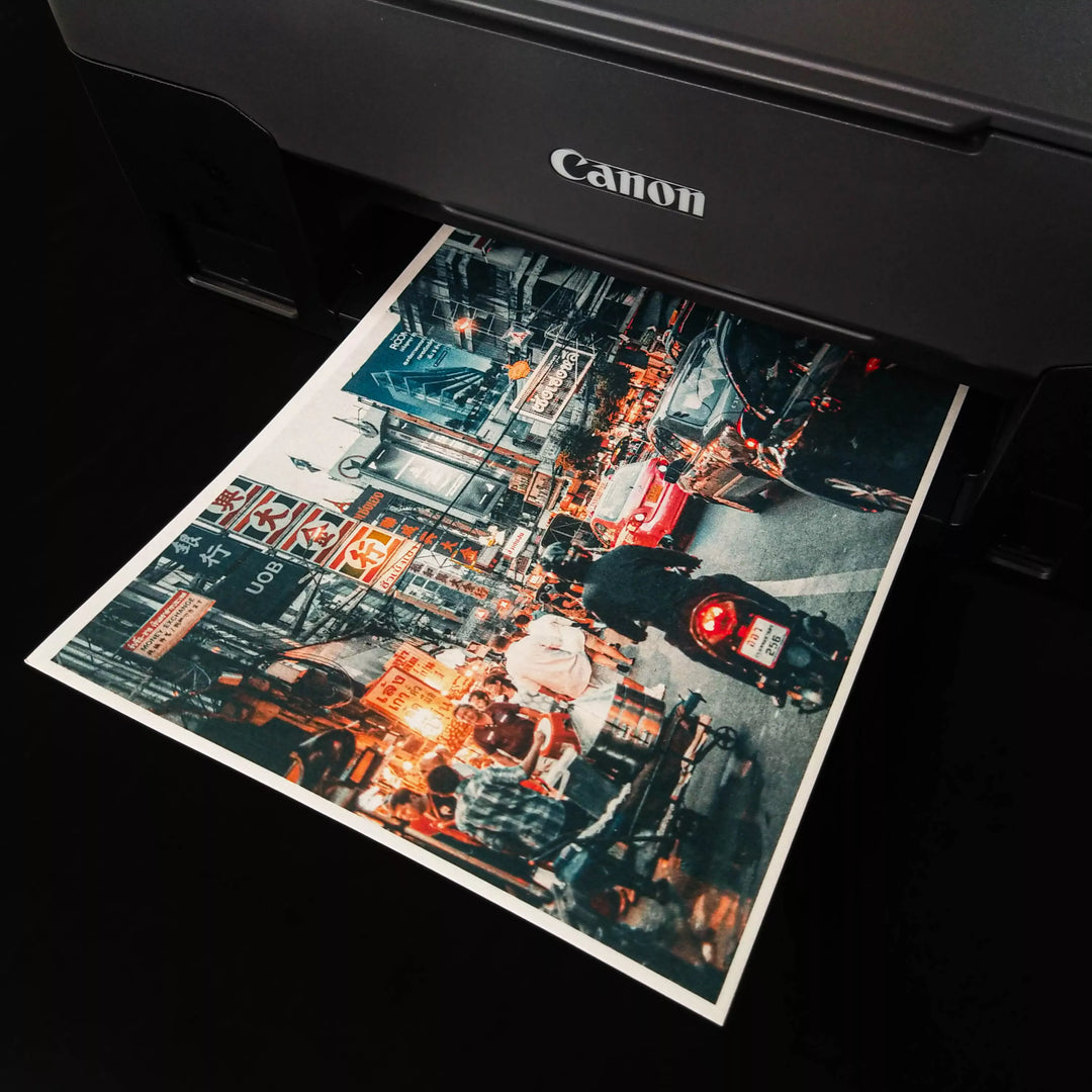 A Canon printer produces a vibrant, colorful photo of a lively urban street scene on Kozo Studio’s Thick White Kozo Paper Roll (200 gsm), capturing people, vehicles, and glowing signs.