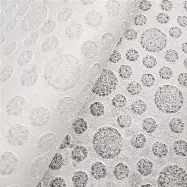 Close-up of two sheets of Handmade Lace Kozo Paper (Bubble) by Kozo Studio with circular, bubble-like patterns. The left sheet is partially lifted to reveal a darker layer beneath.