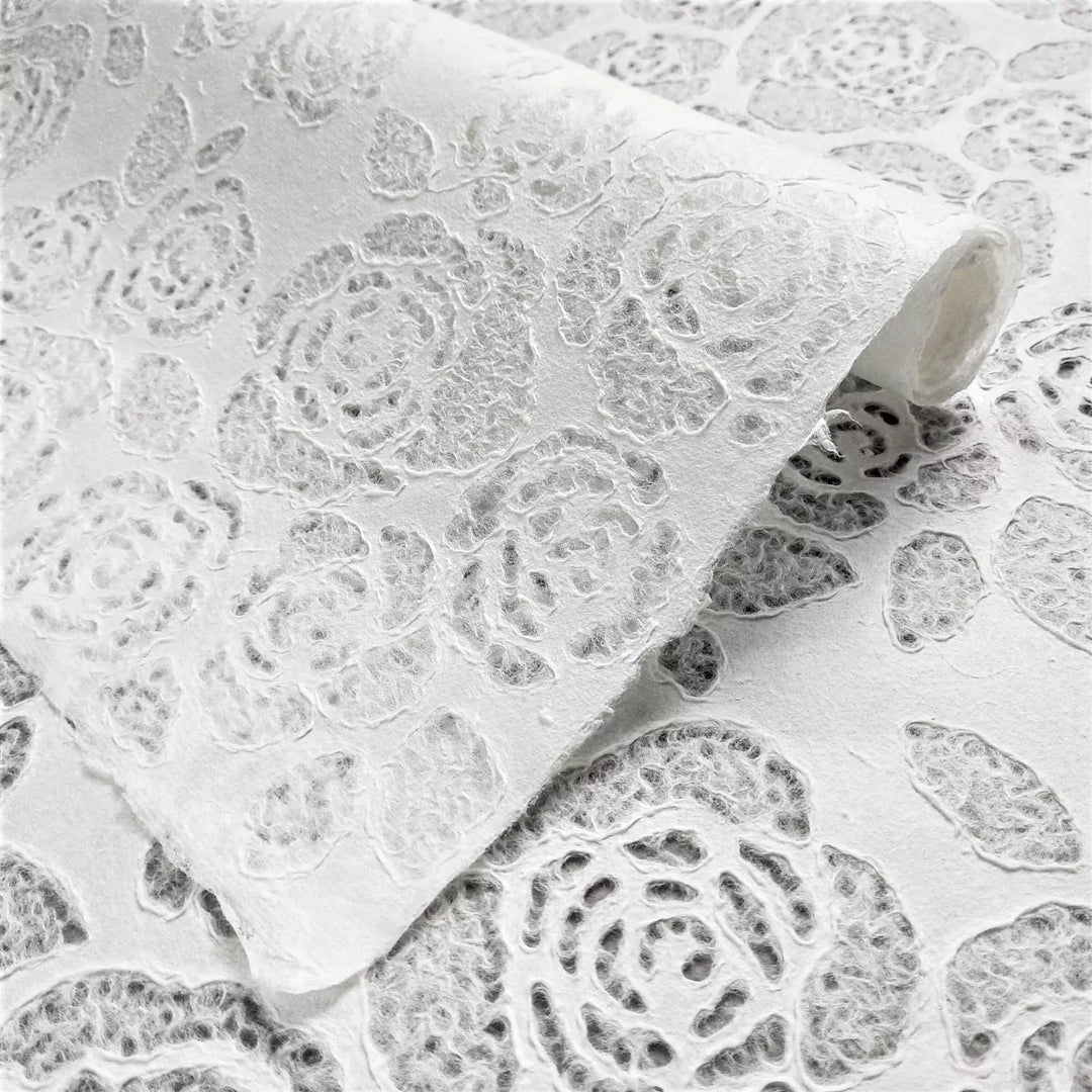 Close-up of floral lace pattern on white handmade mulberry paper from Kozo Studio, showcasing delicate rose and leaf designs ideal for crafts and décor.