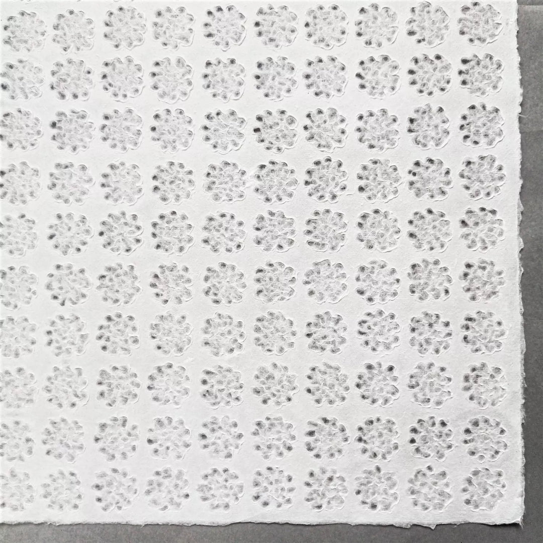 A roll of Handmade Lace Kozo Paper unrolled to display its floral design, highlighting the translucent quality and craftsmanship of Kozo Studio's mulberry paper.