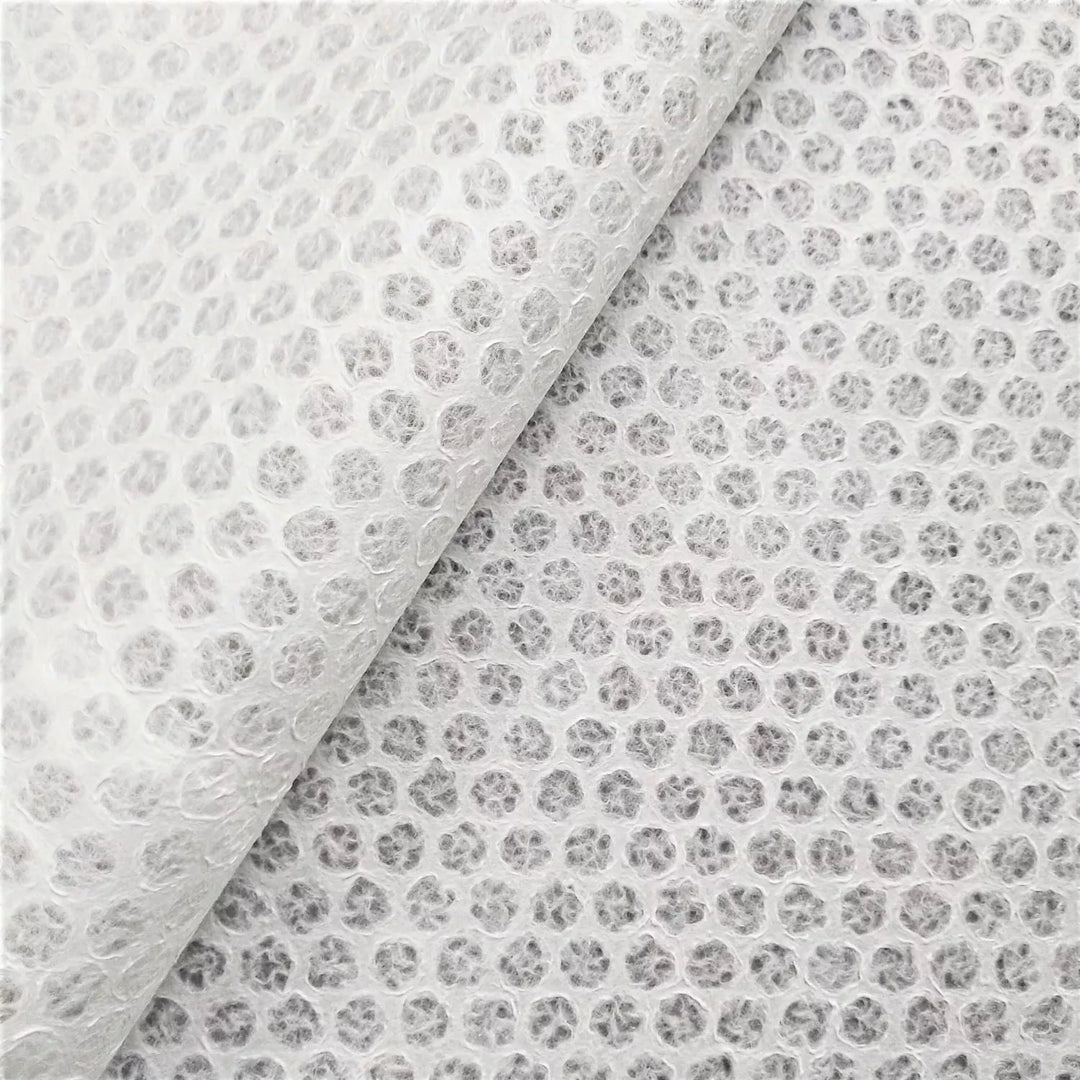 Close-up of translucent Handmade Lace Kozo Mulberry Paper (Polkadot) by Kozo Studio, showing an angled overlap. The small, round dots mimic the delicate texture of rice paper, creating a white, textured pattern across the surface