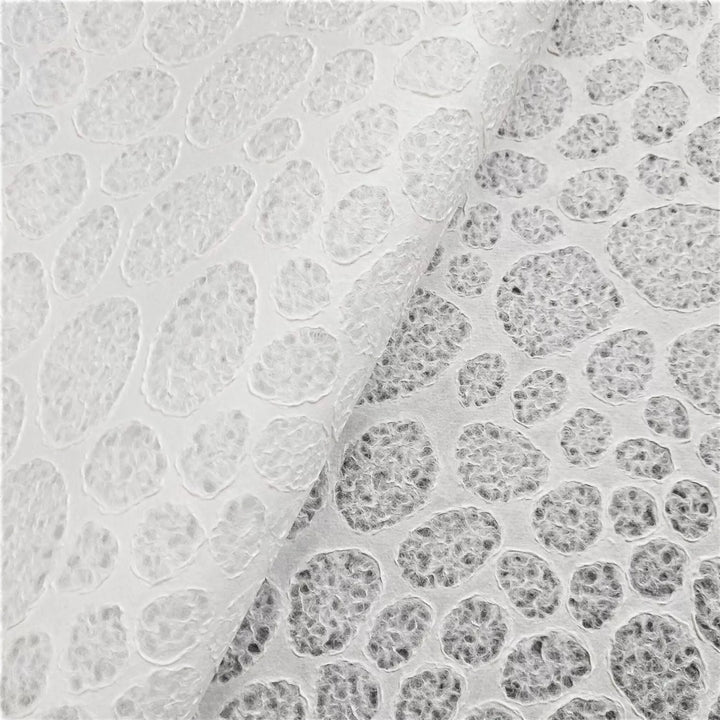 A close-up of Handmade Lace Kozo Paper (Stone) by Kozo Studio showcases a textured surface with irregular, pebble-like patterns in white and gray. It resembles semi-translucent mulberry paper, featuring a slightly raised texture for a unique tactile effect.