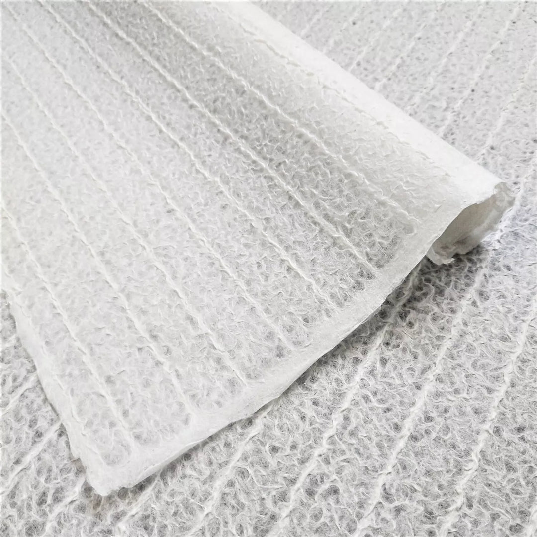 Close-up image of white stripe-patterned mulberry paper handcrafted by Kozo Studio using the Rakusui technique, showcasing the delicate texture and translucency of this premium handmade paper.